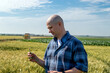 © Andrej - Farmer or agronomist standing in the wheat field examining the yield quality. Agriculture worker checking the wheat straw.