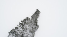 Aerial View Of Snow Covered Lake And Island With Forest On A Snowy Winter Day. 