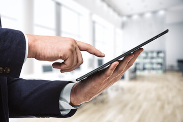 Man using digital tablet in bright sunny office, close up. Technology concept