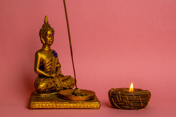 Poster - Small Buddha figurine with a burning candle on a pink background