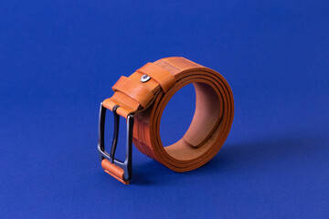 Canvas Print - Brown reptile leather belt on blue fabric background. Fashion and shopping concept