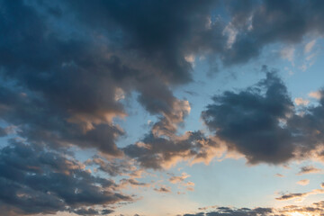 blue sky with dark clouds illuminated by the evening setting sun as a natural background