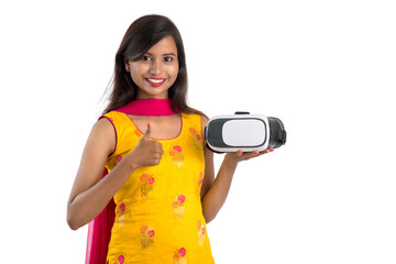 Wall Mural - Indian traditional young girl holding and showing VR device, vr box, goggles, 3D Virtual Reality Glasses headset, Girl with Modern imaging Future technology on white background.