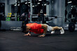 Shot of a muscular and strong guy doing push-ups in a darkened gym with mirrors. Exercise for the whole body, plank workout, sport