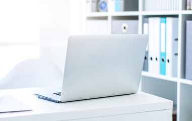 Modern laptop on white table in light office