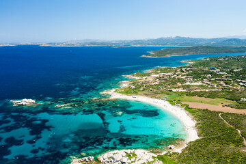 Canvas Print - View from above, stunning aerial view of an empty white sand beach with beach umbrellas and turquoise, clear water illuminated at sunset. Valle Dell’ Erica, Costa Smeralda, Sardinia, Italy.