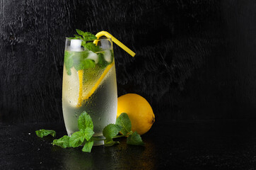 A glass of lemonade with a straw on a black textured background