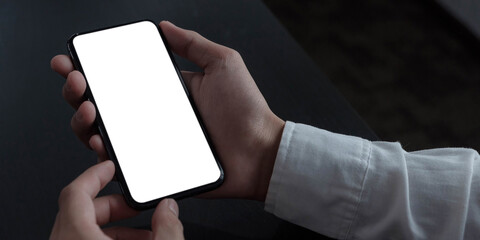 Wall Mural - Mockup image blank white screen cell phone.women hand holding texting using mobile on desk at home office.