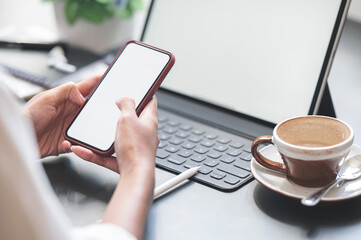 Wall Mural - cropped shot of woman hands using smartphone with blank screen while sitting at office desk.
