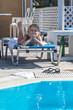 © Nataliia Makarovska - little happy girl lies on a sun lounger in the shade and sunbathes by the pool after swimming, family vacation Greece