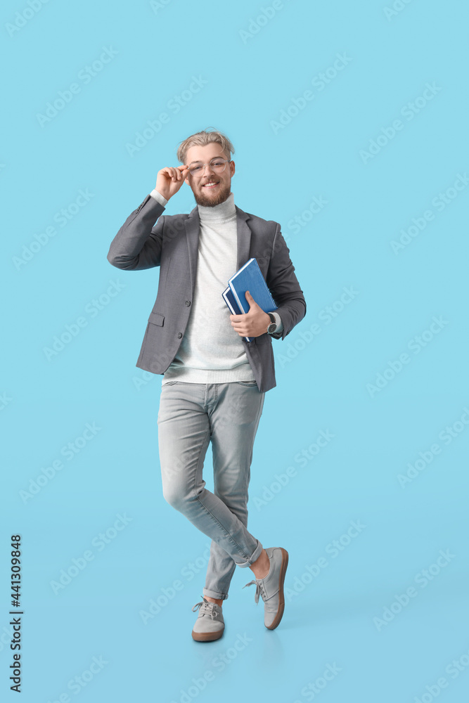 Male student with books on color background