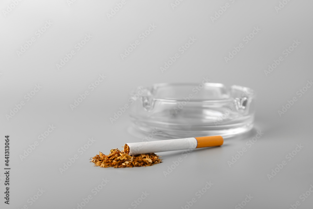 Ash tray with cigarette on light background