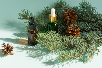 Two dropper bottles of essential oil and fir branches. Christmas aromatherapy and spa concept.