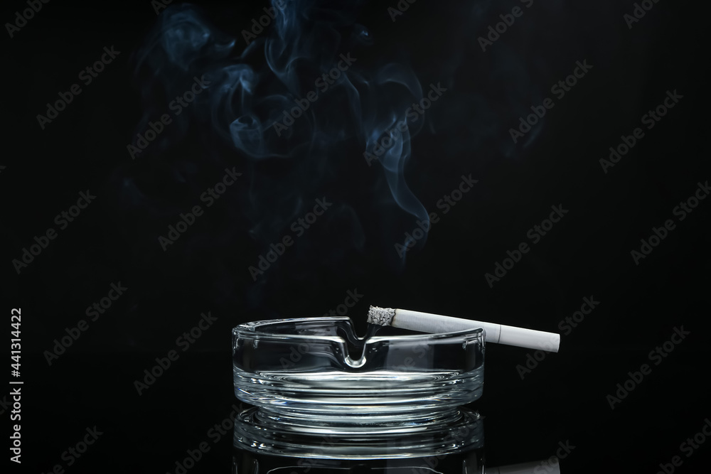 Ash tray with cigarette on dark background