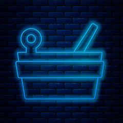 Wall Mural - Glowing neon line Sauna bucket and ladle icon isolated on brick wall background. Vector