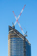 © Austockphoto - Two large cranes on the top of a city skyscraper