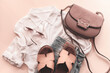 Feminine summer fashion flat lay with blouse, handbag, sunglasses, shorts and slippers on beige background. Top view