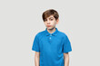 © Red Cristal - Portrait of a pretty boy 12-14 years old looking at the camera over light gray background, dressed in blue t shirt