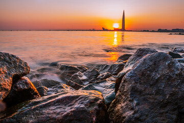 Amazing view of the Lakhta Center skyscraper during a beautiful sunset in St. Petersburg, water waves on a long exposure