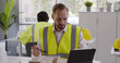 © TommyStockProject - Construction company worker in reflective vest having lunch and using digital tablet in canteen