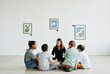 © Seventyfour - Full length view at diverse group of children sitting in circle during class in art gallery, copy space