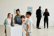 © Seventyfour - Multi-ethnic group of children looking at sculptures in modern art gallery, copy space
