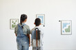 © Seventyfour - Minimal back view at two children visiting art gallery and looking at modern abstract paintings, copy space