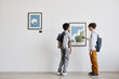 © Seventyfour - Minimal back view portrait of two schoolboys looking at abstract paintings in modern art gallery, copy space
