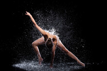 Slender Woman In Wet Sports Underwear Dancing On Surface Of Water. Ballet Dancer Is Making Tricks In Liquid Splashes. Athletic Body Is Glisten In Studio Light. Freedom, Freshness Concept. Modern Art.