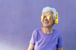 © ADDICTIVE STOCK - Smiling elderly woman in sunglasses listening to music from headphones