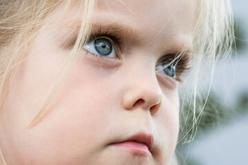 Closeup shot of face and blue eyes of a beautiful blond girl looking defiantly