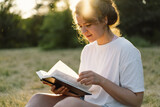 Fototapeta  - Christian woman holds bible in her hands. Reading the Holy Bible in a field during beautiful sunset. Concept for faith, spirituality and religion