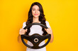 © deagreez - Portrait of attractive cheery content wavy-haired girl holding steering wheel control isolated over bright yellow color background
