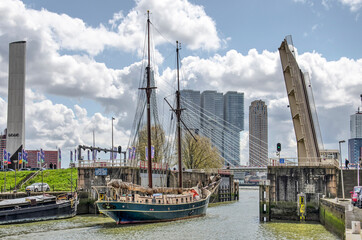 Rotterdam, the Netherlands, May 2, 2021: two mast historic sail yacht laeving Leuvehaven harbour, with Erasmus bridge in the background