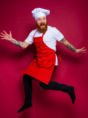 Wall Mural - happy chef with beard and red apron jumps