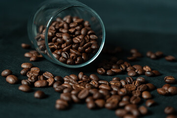 Dark roasted coffee beans with glass on black background