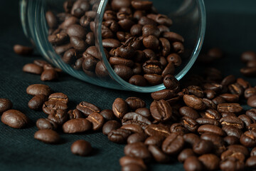 Dark roasted coffee beans with glass on black background