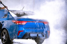 Manual Car Wash With White Soap, Foam On The Body. Washing Car Using High Pressure Water. Blue Car