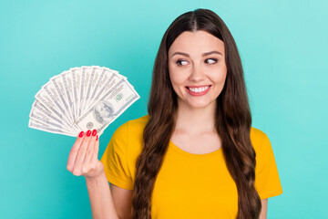 Sticker - Photo of joyful millennial lady hold look dollars wear yellow t-shirt isolated on vivid teal color background