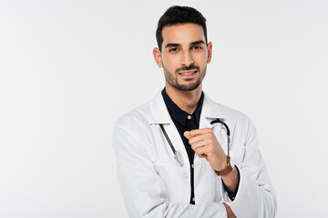 Canvas Print - Positive arabian doctor in white coat looking a camera isolated on grey