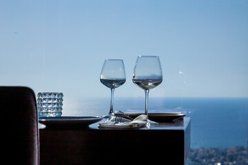 served table in a restaurant or cafe with a panoramic window overlooking modern city buildings and the sea on a sunny day