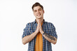 © Cookie Studio - Thank you. Smiling young man nod grateful, holds hands in pray beg gesture, appreciate something, express gratitude, standing against white background
