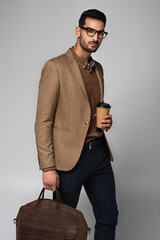 Canvas Print - Stylish muslim businessman holding paper cup and handbag isolated on grey