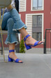 © Mykola - Women's legs in blue cropped denim jeans and sandals in the city street. Trendy elegant casual outfit. Details of everyday summer look.