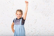 Pretty schoolgirl in blue dress making funny poses, copy space in empty room