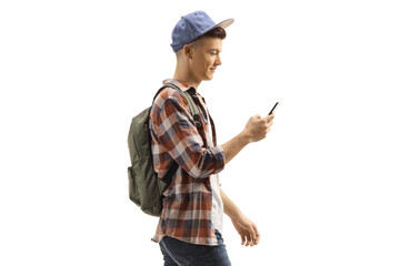 Wall Mural - Student with a backpack and cap walking and looking at his mobile phone