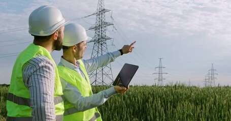 Wall Mural - two power engineers stand with an electronic tablet in their hands against the background of a high-