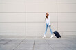 © Mego-studio - Young woman carrying a suitcase outdoors.