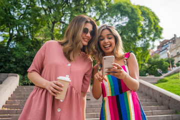 Two friends using mobile phone outdoors.