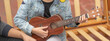 little girl plays ukulele smiling wearing denim jacket outdoors concep music